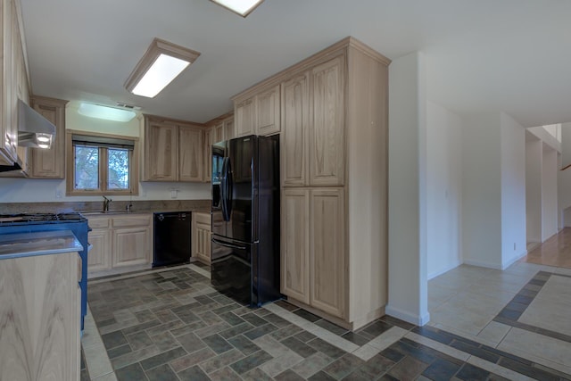 kitchen featuring visible vents, wall chimney range hood, light brown cabinetry, black appliances, and a sink