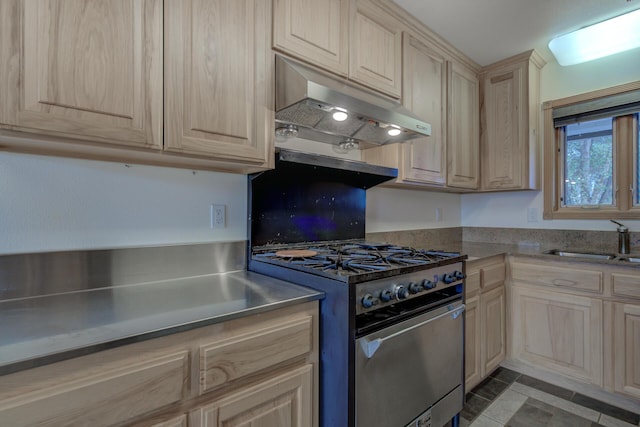 kitchen featuring a sink, under cabinet range hood, light brown cabinets, and stainless steel range with gas stovetop