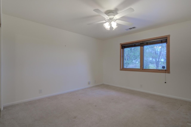 empty room featuring light carpet, a ceiling fan, visible vents, and baseboards