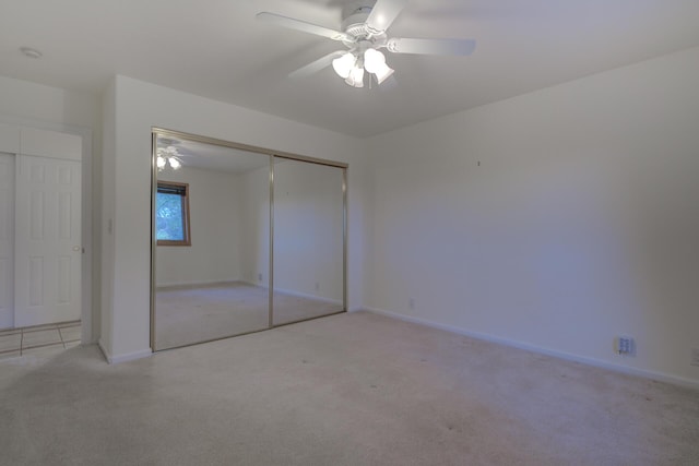 unfurnished bedroom with baseboards, ceiling fan, a closet, and light colored carpet