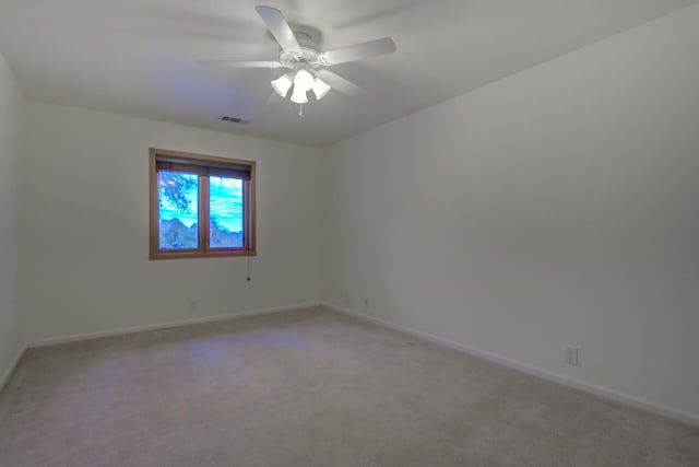 spare room featuring a ceiling fan, visible vents, light carpet, and baseboards