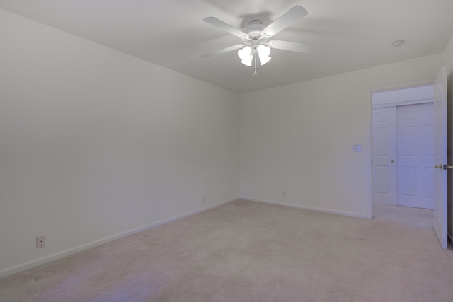 spare room with ceiling fan, baseboards, and light colored carpet