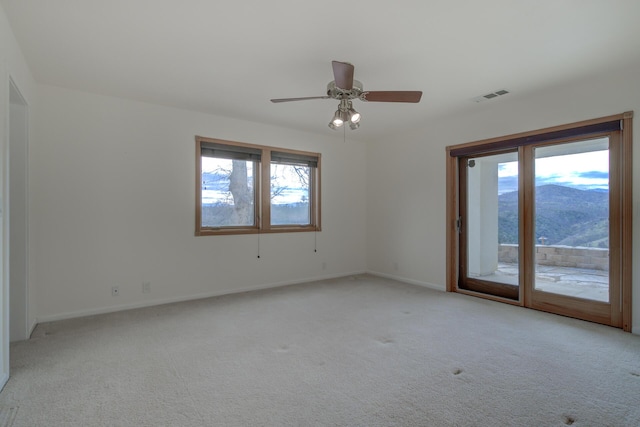 spare room featuring visible vents, baseboards, a ceiling fan, light colored carpet, and a mountain view