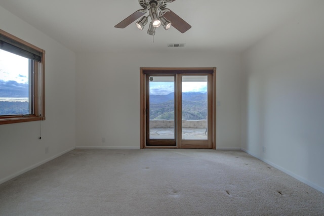 spare room featuring visible vents, a mountain view, light carpet, and baseboards