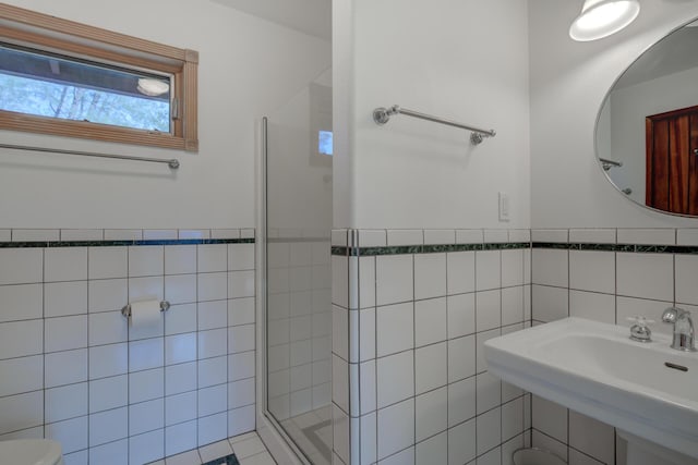 bathroom with a sink, wainscoting, a shower stall, and tile walls