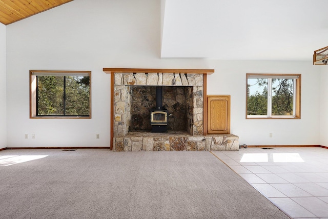 unfurnished living room with vaulted ceiling, light tile patterned flooring, and a wood stove