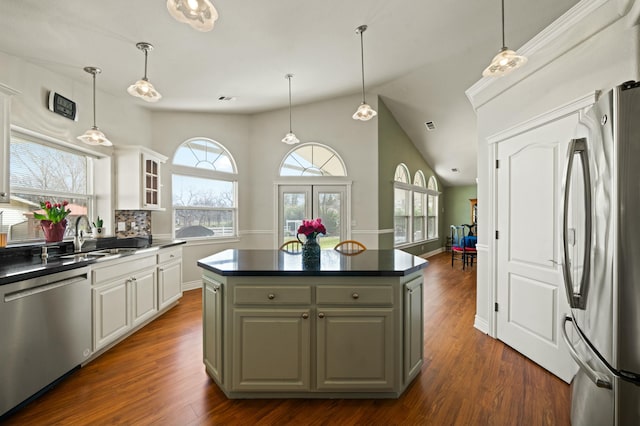 kitchen with stainless steel appliances, dark countertops, dark wood finished floors, and glass insert cabinets