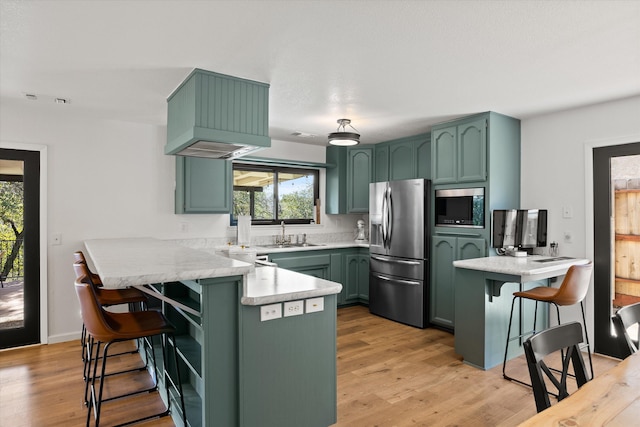 kitchen featuring a breakfast bar, stainless steel fridge with ice dispenser, built in microwave, green cabinetry, and kitchen peninsula