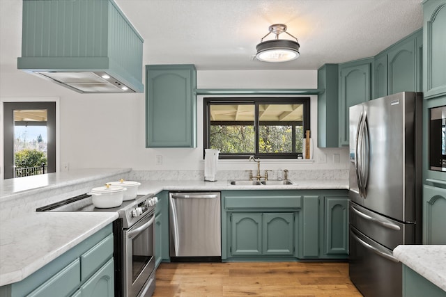 kitchen featuring sink, custom exhaust hood, green cabinets, stainless steel appliances, and plenty of natural light