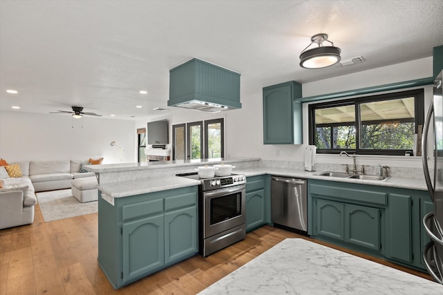 kitchen with sink, hardwood / wood-style flooring, appliances with stainless steel finishes, custom exhaust hood, and kitchen peninsula