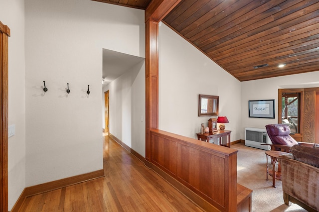 hallway featuring wooden ceiling, visible vents, baseboards, vaulted ceiling, and light wood finished floors