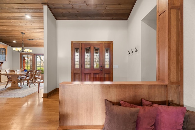 foyer entrance with a chandelier, wooden ceiling, baseboards, and light wood-style floors