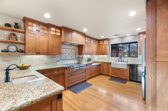 kitchen featuring stainless steel gas cooktop, open shelves, light stone counters, and a sink