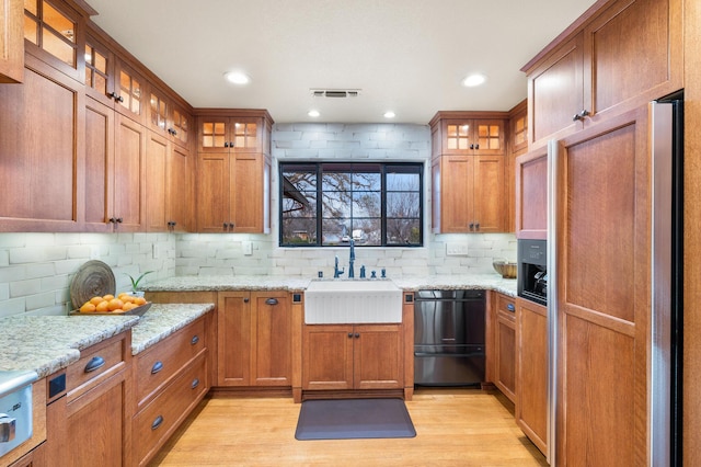 kitchen with a sink, visible vents, paneled built in fridge, dishwasher, and glass insert cabinets