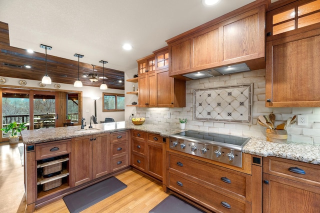 kitchen with brown cabinets, stainless steel gas cooktop, decorative light fixtures, and open shelves