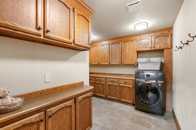 clothes washing area featuring washer / dryer, a textured ceiling, visible vents, and cabinet space