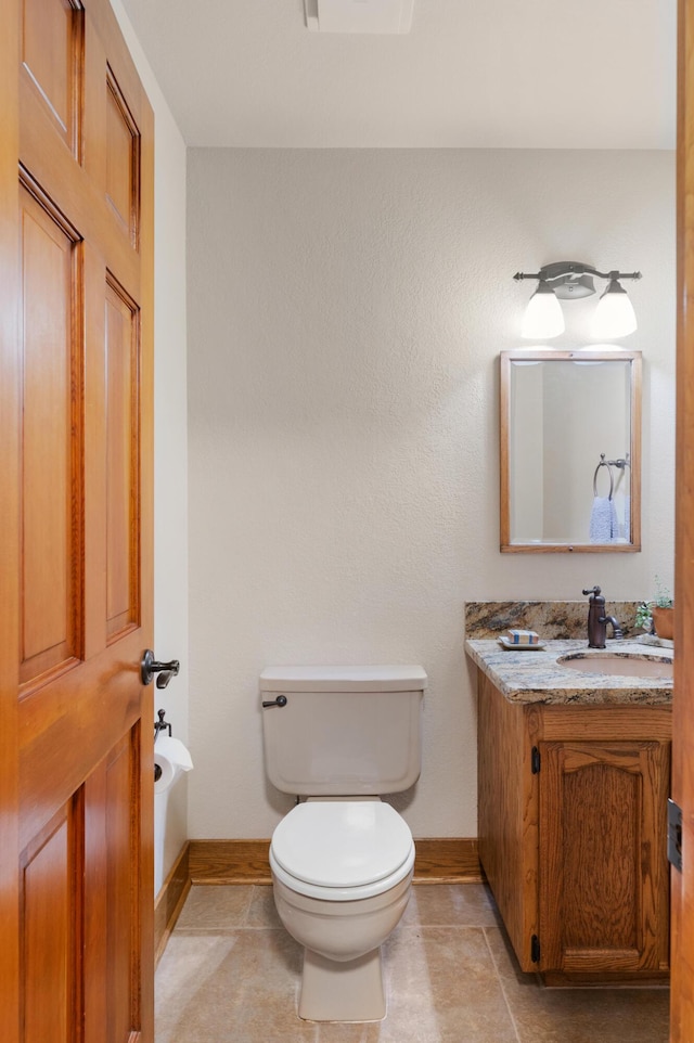 bathroom featuring baseboards, vanity, toilet, and tile patterned floors