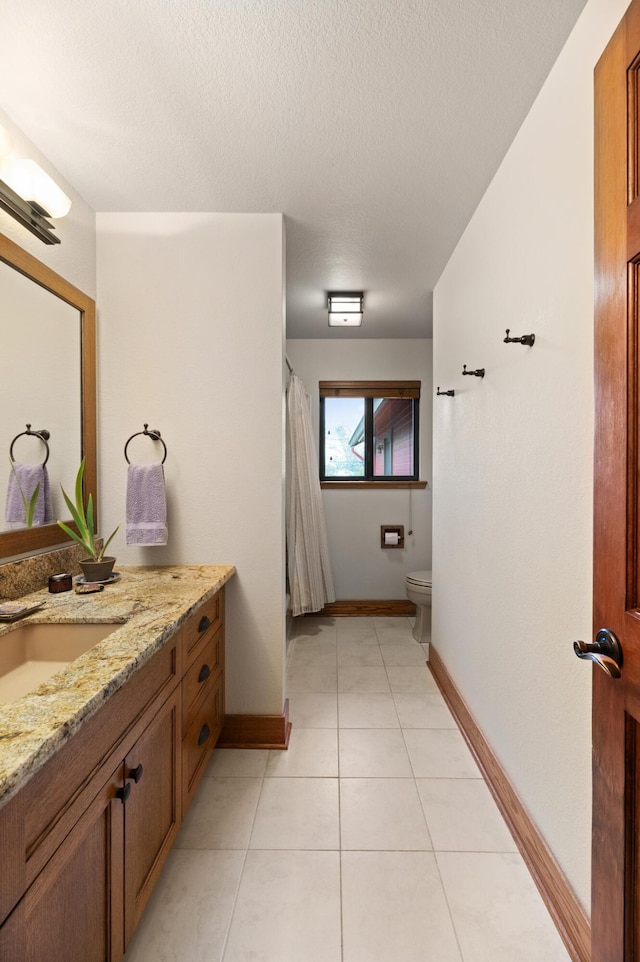 bathroom featuring toilet, vanity, a textured ceiling, baseboards, and tile patterned floors