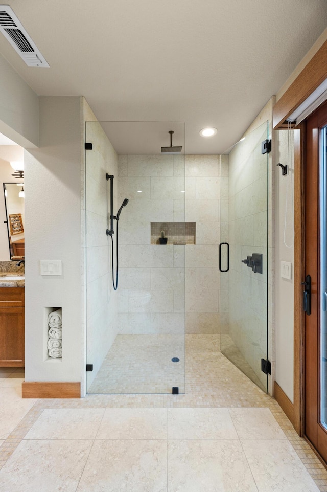 bathroom with a stall shower, visible vents, and a sink