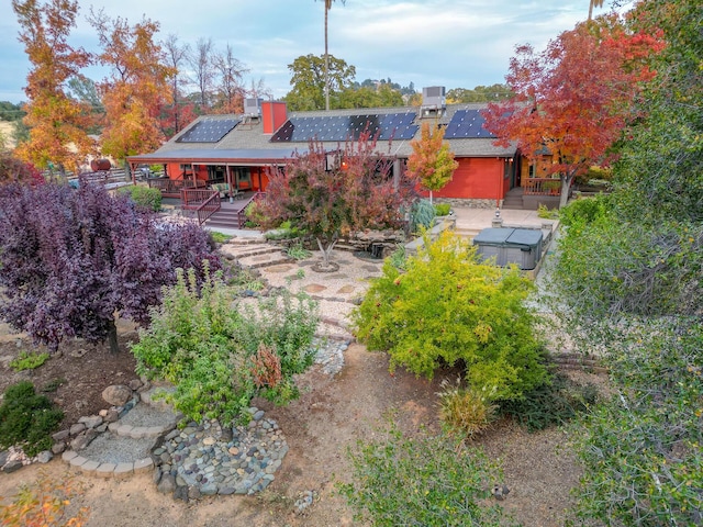 back of house with roof mounted solar panels