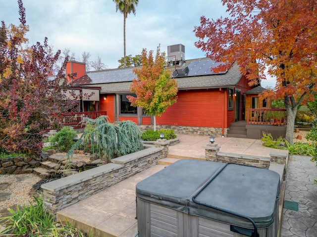 rear view of house featuring a shingled roof, central AC, a patio, and a hot tub