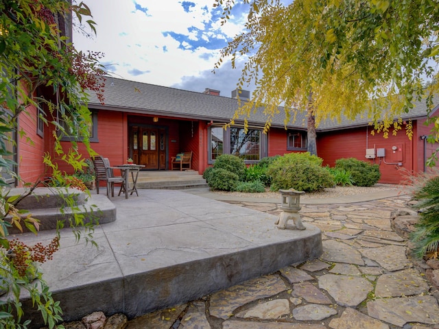 back of property featuring a patio area and roof with shingles