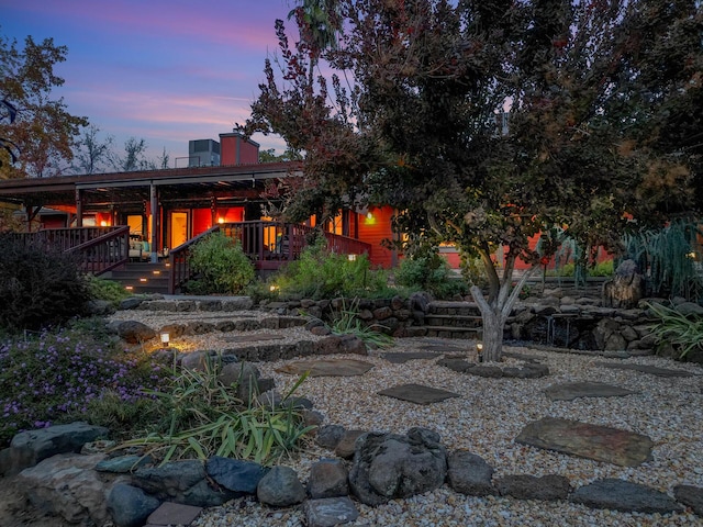 back of house at dusk featuring a deck