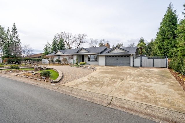 view of front of house with a gate, driveway, a chimney, and an attached garage