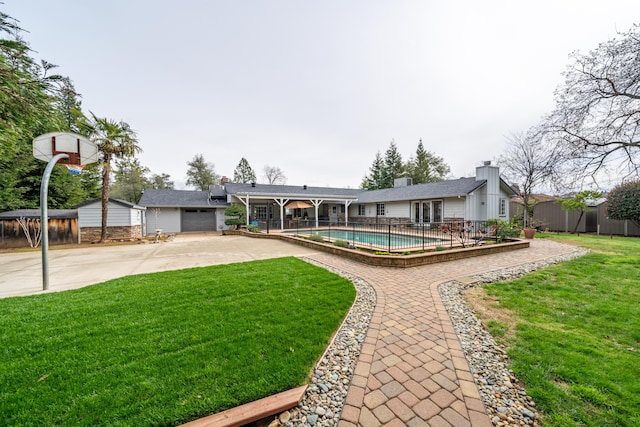 rear view of house featuring a fenced in pool, an outbuilding, a lawn, fence, and a shed