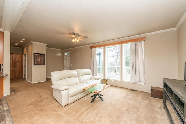 carpeted living room with ornamental molding and ceiling fan