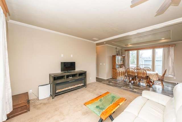 living room featuring ceiling fan, hardwood / wood-style flooring, a tray ceiling, and ornamental molding