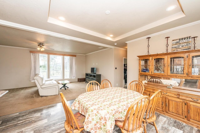 dining space with ceiling fan, ornamental molding, and a raised ceiling