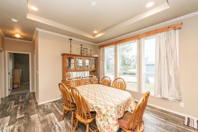 dining room featuring ornamental molding, dark wood-type flooring, and a raised ceiling