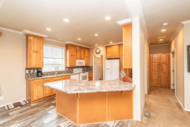 kitchen featuring tasteful backsplash, white appliances, sink, a kitchen bar, and kitchen peninsula