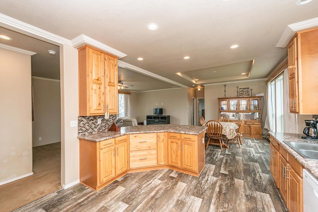 kitchen with ornamental molding, white dishwasher, a raised ceiling, and kitchen peninsula