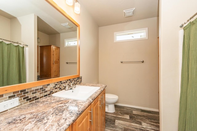 bathroom featuring hardwood / wood-style flooring, vanity, toilet, and backsplash