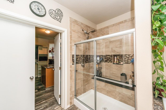 bathroom with hardwood / wood-style floors and a shower with shower door