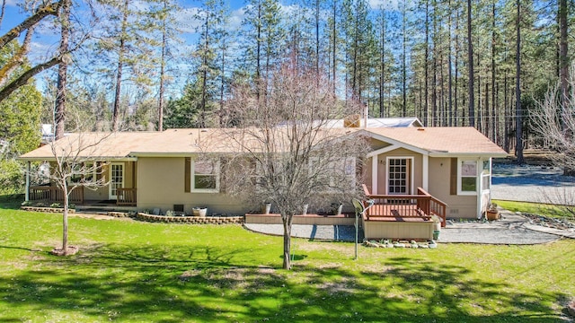 back of house featuring crawl space, a lawn, a wooden deck, and stucco siding