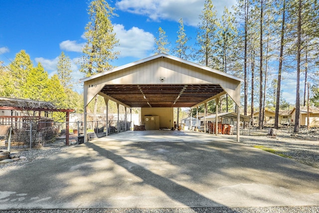 view of parking / parking lot with driveway, fence, and a detached carport