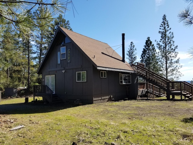 view of home's exterior featuring french doors, roof with shingles, stairs, and a lawn