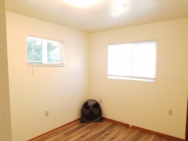 spare room with baseboards and light wood-type flooring
