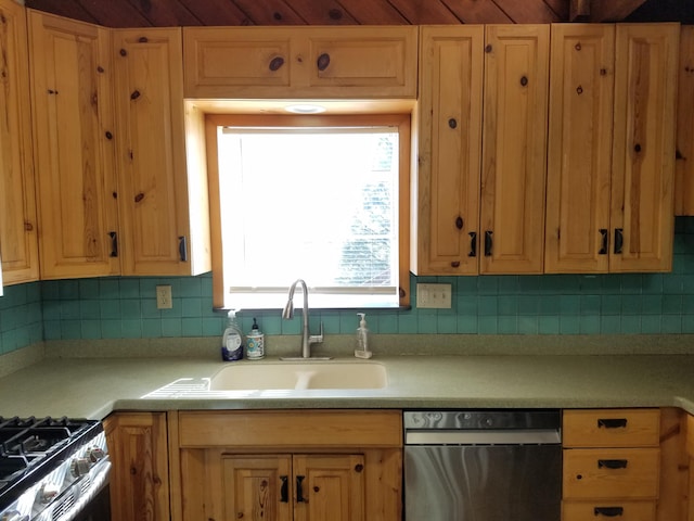 kitchen featuring light countertops, a sink, backsplash, and appliances with stainless steel finishes