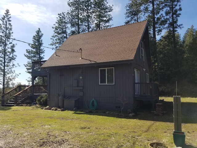 back of house featuring roof with shingles, crawl space, and a yard