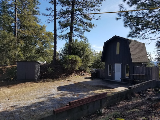 view of yard with an outdoor structure, a patio, fence, and a storage shed