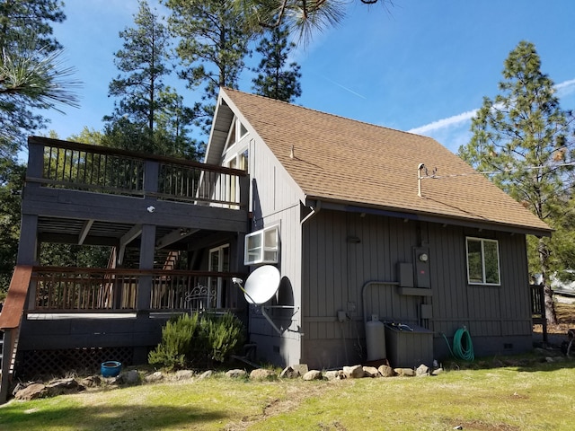 rear view of property featuring a lawn, a shingled roof, a wooden deck, and crawl space