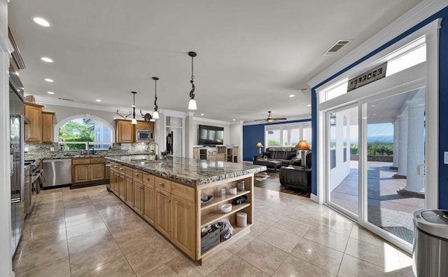 kitchen featuring appliances with stainless steel finishes, an island with sink, pendant lighting, backsplash, and sink