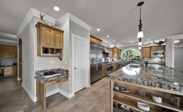 kitchen with built in appliances, wall chimney range hood, decorative light fixtures, backsplash, and sink