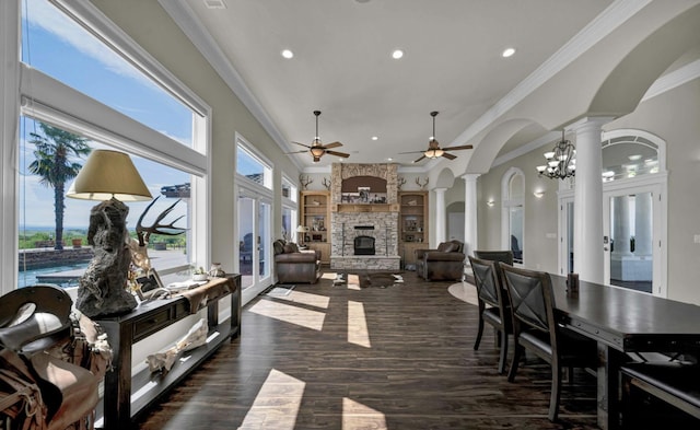 interior space with ceiling fan with notable chandelier, a wealth of natural light, decorative columns, and a fireplace