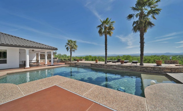 view of swimming pool featuring ceiling fan, a mountain view, and a patio area