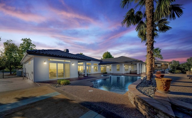 pool at dusk featuring a patio area